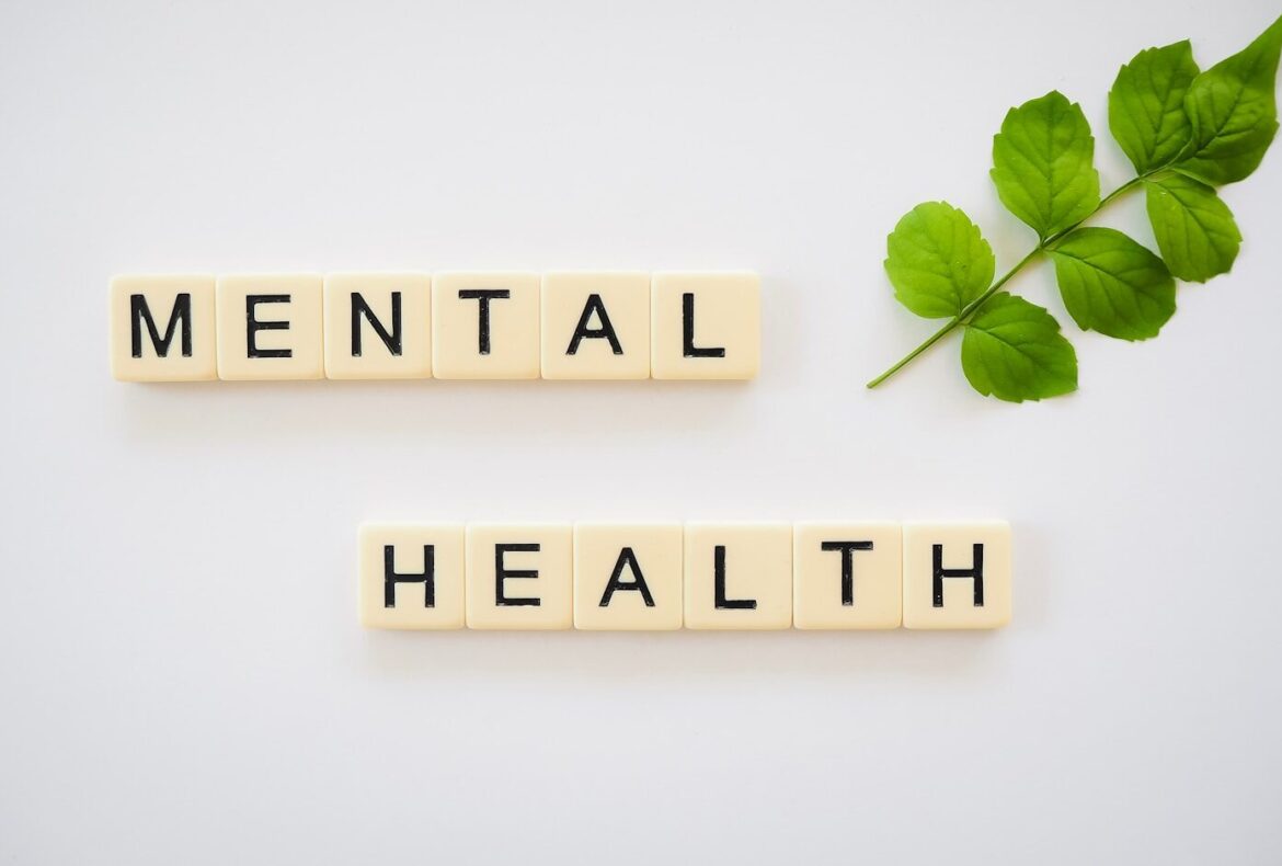 Photo by Total Shape the word mental health spelled with scrabbles next to a green leaf