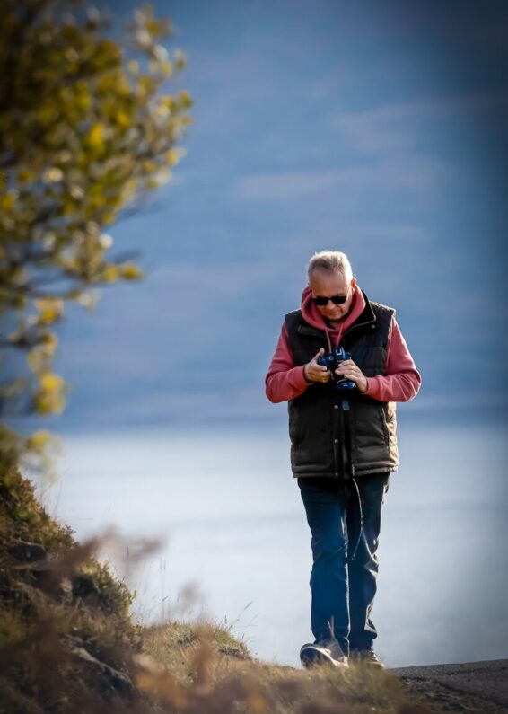 Man looking at binoculars outdoors by a lake